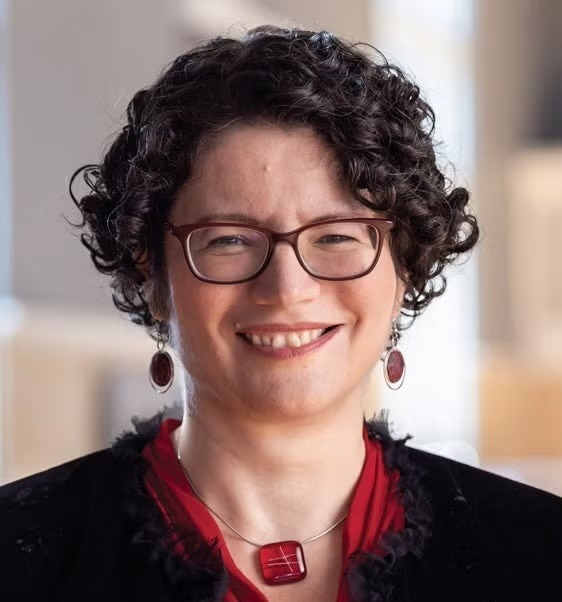 Headshot of Tanya Berger-Wolf, a woman with short curly dark hair and glasses, wearing a red top and black jacket with a red necklace.
